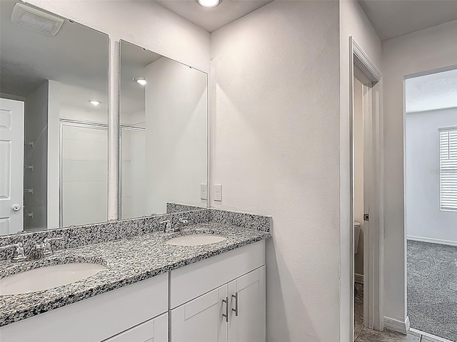 full bath featuring double vanity, a shower with door, and baseboards