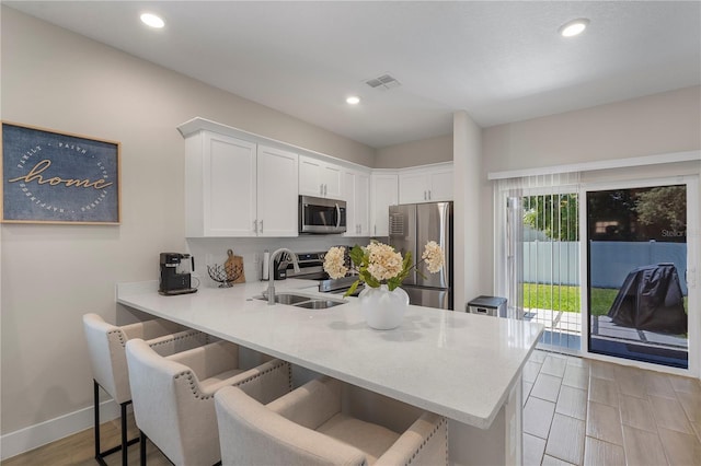 146 E 15th St, Apopka, FL 32703 - kitchen with stainless steel appliances, a sink, white cabinets, a peninsula, and a kitchen bar
