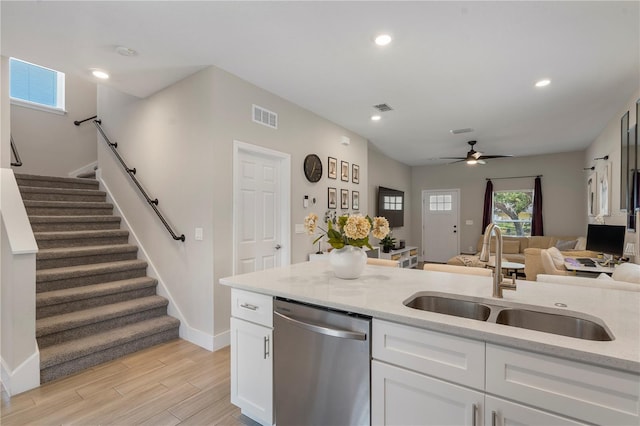 146 E 15th St, Apopka, FL 32703 - kitchen with stainless steel dishwasher, a sink, baseboards, a ceiling fan, and white cabinets
