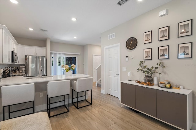 146 E 15th St, Apopka, FL 32703 - kitchen with stainless steel appliances, a peninsula, a breakfast bar, white cabinets, and light countertops