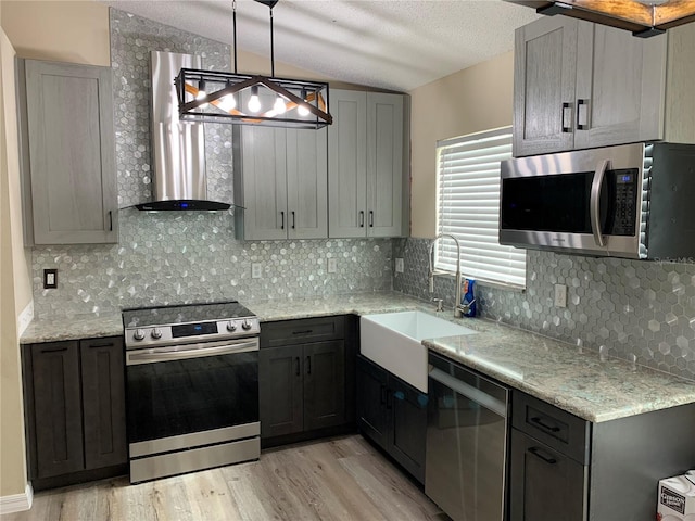 1112 Winding Water Way, Clermont, FL 34714 - kitchen with appliances with stainless steel finishes, wall chimney exhaust hood, a sink, light wood-type flooring, and vaulted ceiling