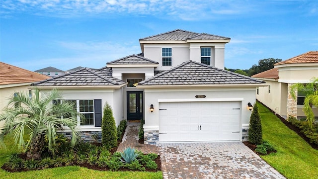 view of front of house featuring an attached garage, driveway, stucco siding, stone siding, and a tiled roof