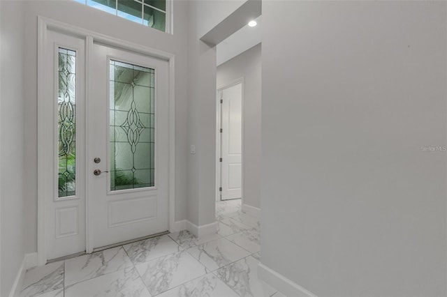 foyer entrance featuring light marble finish floors and baseboards
