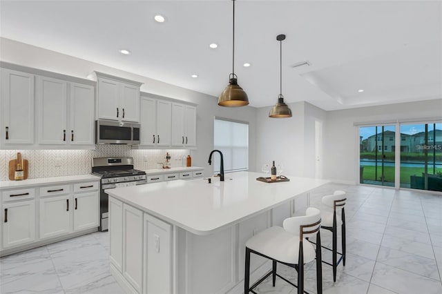kitchen featuring stainless steel appliances, light marble finish floors, recessed lighting, a center island with sink, and light countertops