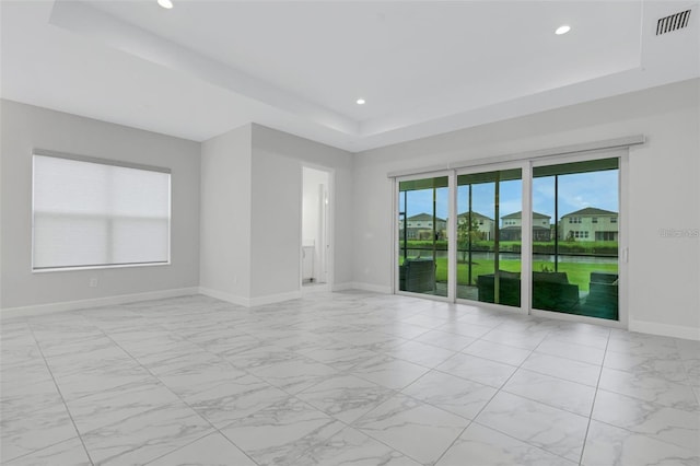 spare room featuring a raised ceiling, light marble finish floors, recessed lighting, and baseboards