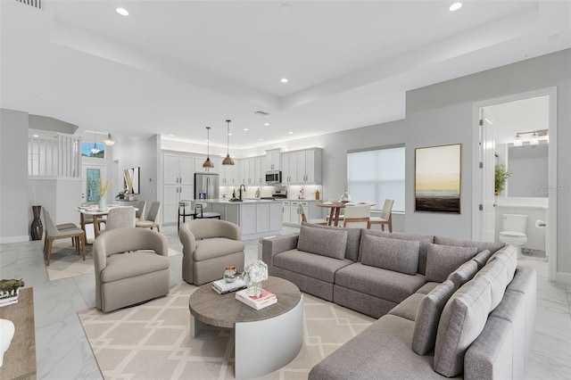 living room with light marble finish flooring, recessed lighting, a tray ceiling, and baseboards