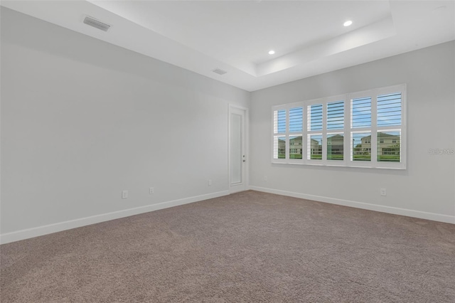 unfurnished room featuring a raised ceiling, baseboards, recessed lighting, and carpet floors