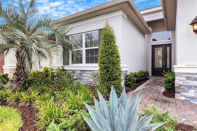 doorway to property with stucco siding and stone siding