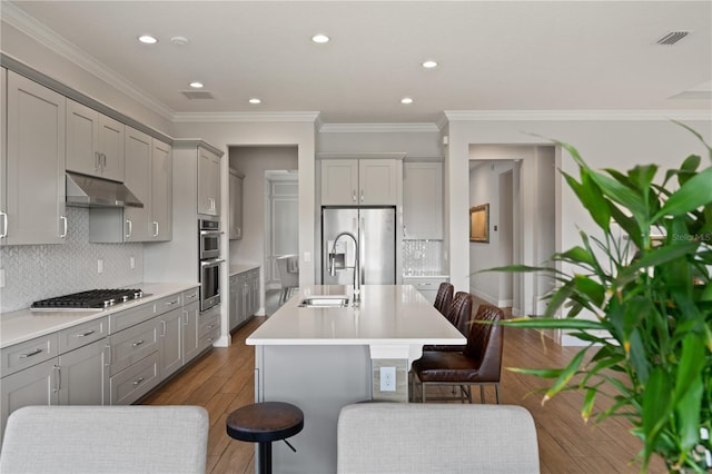 10529 Royal Cypress Way, Orlando, FL 32836 - kitchen featuring appliances with stainless steel finishes, gray cabinets, under cabinet range hood, a kitchen bar, and dark wood-style floors