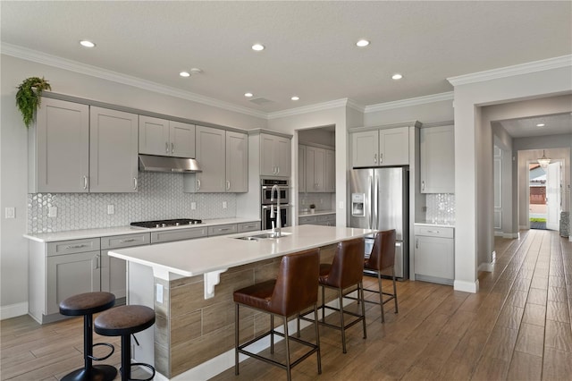 10529 Royal Cypress Way, Orlando, FL 32836 - kitchen featuring stainless steel appliances, gray cabinetry, under cabinet range hood, a breakfast bar, and a kitchen island with sink