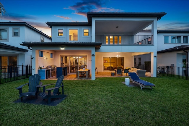 10529 Royal Cypress Way, Orlando, FL 32836 - back of property at dusk featuring a balcony, stucco siding, an outdoor kitchen, outdoor lounge area, and a patio area