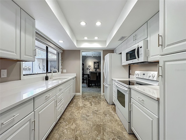 103 Red Cedar Dr, Longwood, FL 32779 - kitchen with white appliances, a sink, a tray ceiling, white cabinets, and recessed lighting