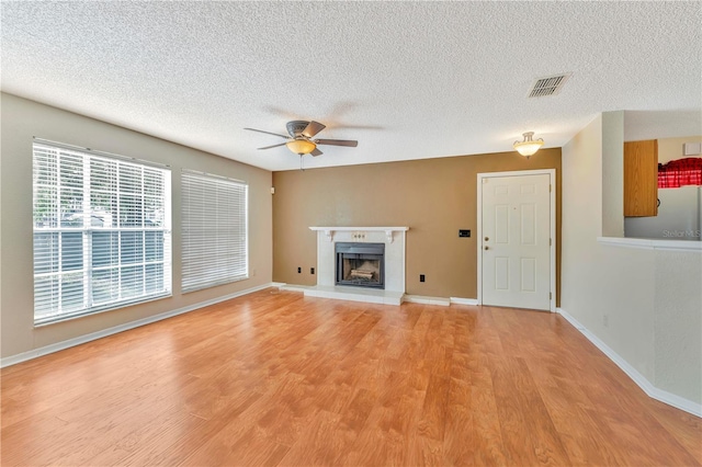 935 Northern Dancer Way Unit 107, Casselberry, FL 32707 - unfurnished living room featuring ceiling fan, a textured ceiling, light wood-style floors, a fireplace with raised hearth, and baseboards