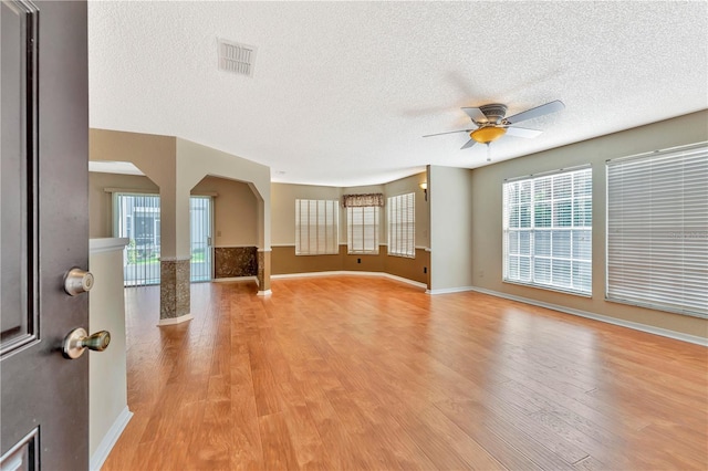 935 Northern Dancer Way Unit 107, Casselberry, FL 32707 - unfurnished living room with a textured ceiling, arched walkways, a ceiling fan, light wood-style floors, and baseboards