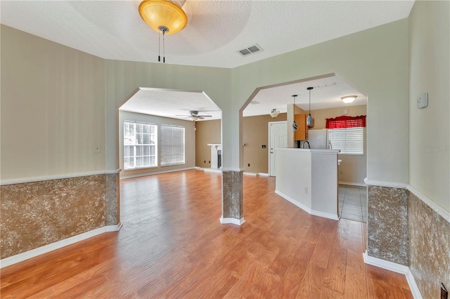 935 Northern Dancer Way Unit 107, Casselberry, FL 32707 - unfurnished living room featuring arched walkways, ceiling fan, wood finished floors, a textured ceiling, and baseboards