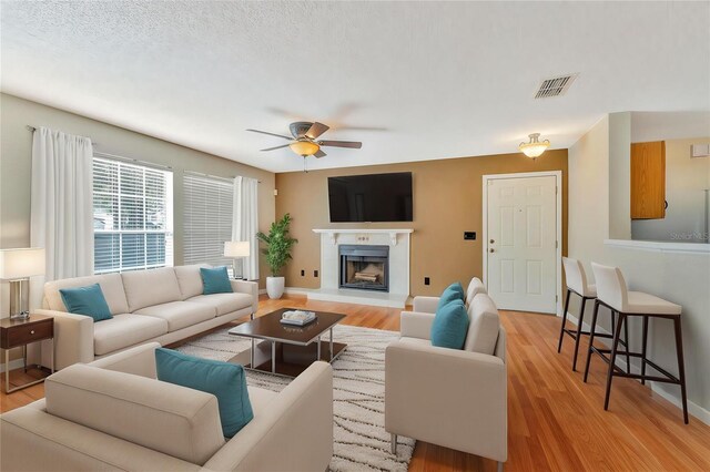935 Northern Dancer Way Unit 107, Casselberry, FL 32707 - living area with ceiling fan, light wood finished floors, a fireplace with raised hearth, and baseboards