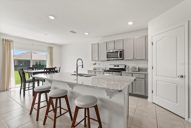 850 Lazio Cir, Debary, FL 32713 - kitchen with appliances with stainless steel finishes, a sink, gray cabinetry, a breakfast bar, and a kitchen island with sink