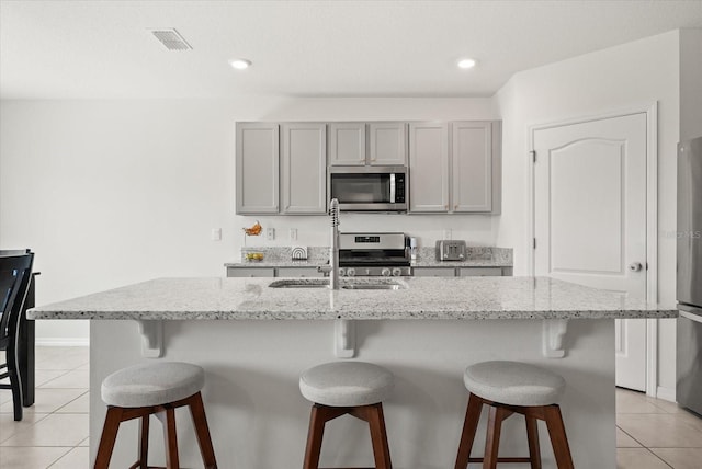 850 Lazio Cir, Debary, FL 32713 - kitchen featuring appliances with stainless steel finishes, gray cabinets, light tile patterned floors, a kitchen island with sink, and recessed lighting