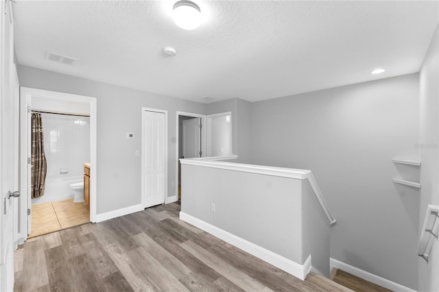 1902 Hailsham Ct, Orlando, FL 32824 - unfurnished bedroom featuring a textured ceiling, baseboards, connected bathroom, and wood finished floors