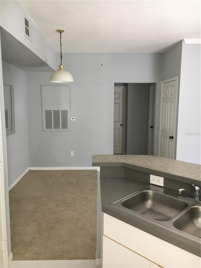 kitchen featuring carpet, a sink, baseboards, and decorative light fixtures