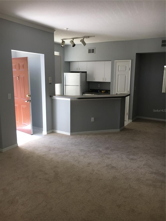 kitchen with freestanding refrigerator, white cabinets, carpet flooring, and baseboards