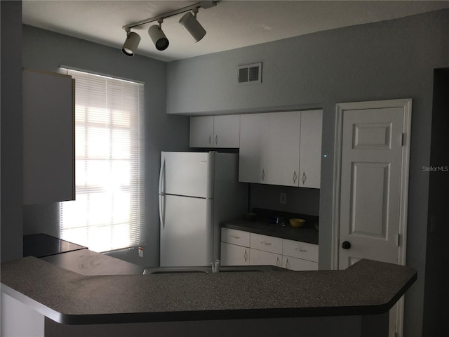kitchen with freestanding refrigerator, dark countertops, white cabinets, and plenty of natural light