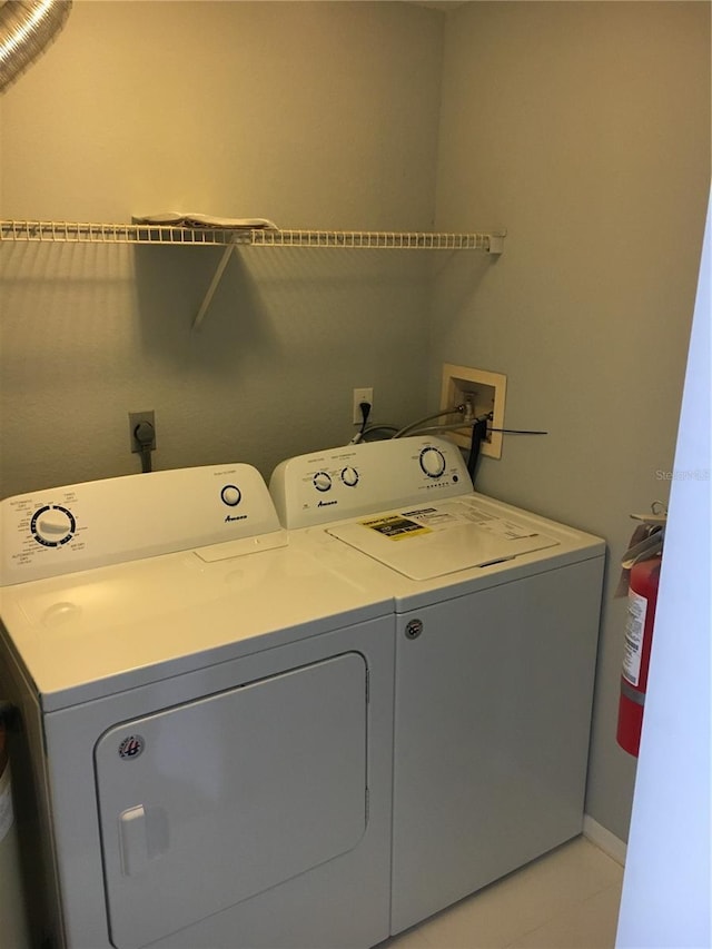 laundry area with washing machine and clothes dryer, light tile patterned flooring, and baseboards
