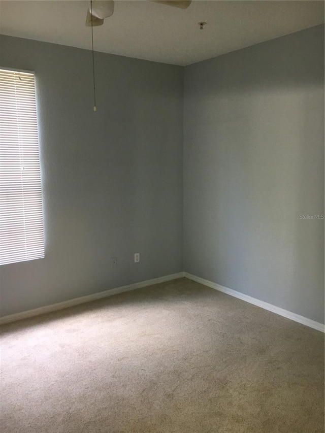 empty room featuring carpet floors, baseboards, a pendent fire sprinkler, and a ceiling fan