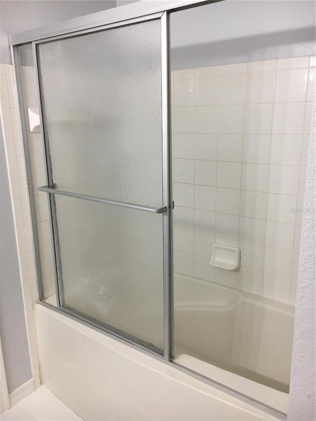 bathroom with shower / bath combination with glass door