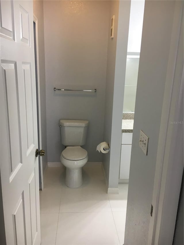 bathroom with toilet, tile patterned flooring, baseboards, and vanity