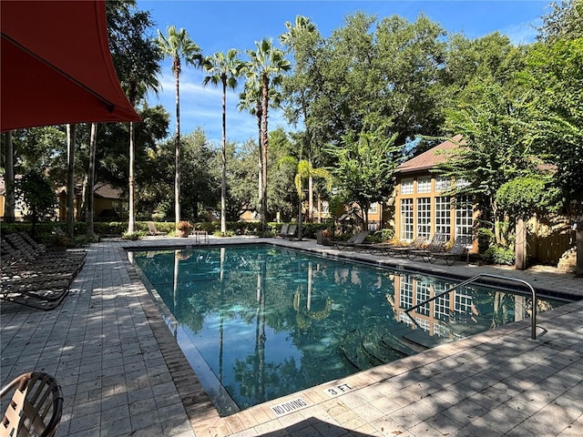 community pool featuring a patio area and view of scattered trees