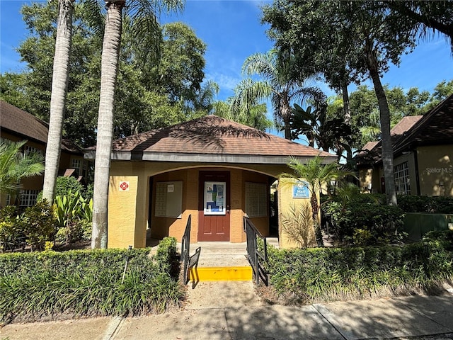view of front facade featuring covered porch, stucco siding, and a shingled roof