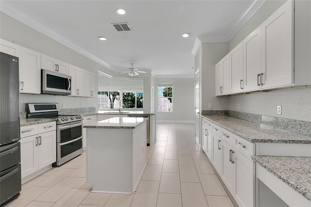 7900 Saint Giles Pl, Orlando, FL 32835 - kitchen featuring appliances with stainless steel finishes, crown molding, a ceiling fan, a kitchen island, and a sink