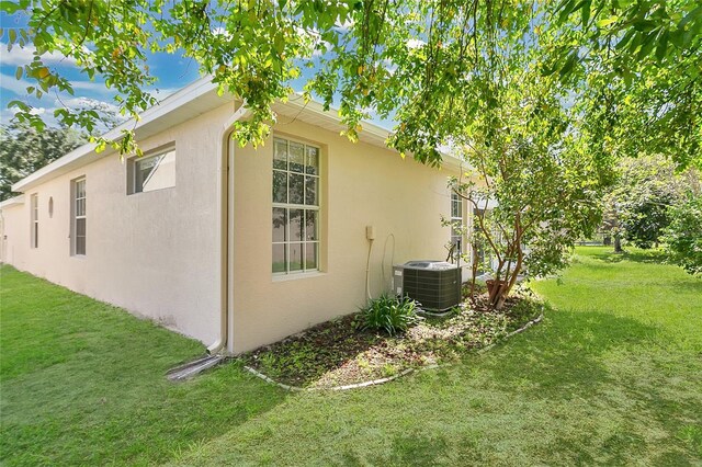7900 Saint Giles Pl, Orlando, FL 32835 - view of side of home with central air condition unit, stucco siding, and a yard