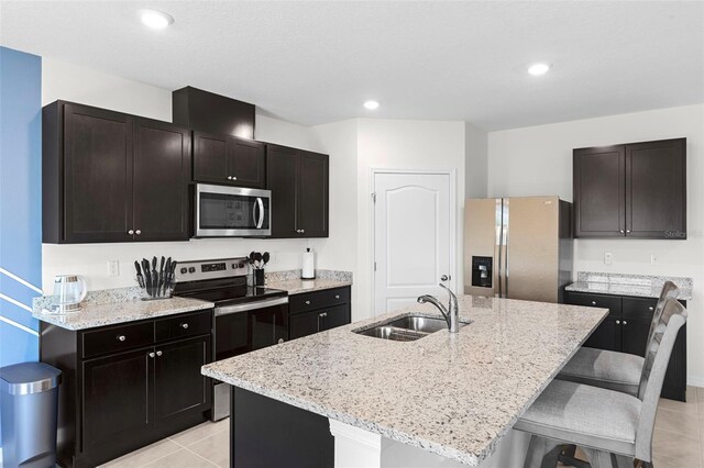 616 Griffon Ave, Lake Alfred, FL 33850 - kitchen featuring appliances with stainless steel finishes, a sink, light tile patterned floors, a kitchen breakfast bar, and light stone countertops