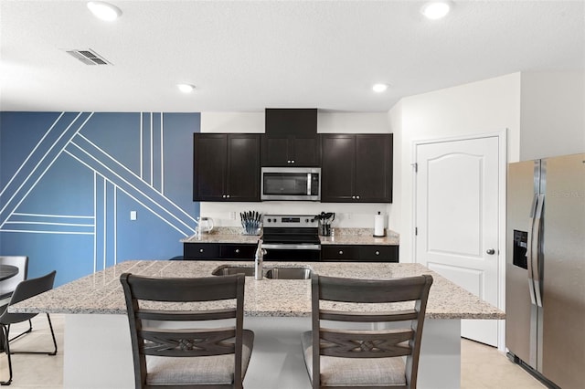 616 Griffon Ave, Lake Alfred, FL 33850 - kitchen featuring appliances with stainless steel finishes, a sink, a breakfast bar area, a decorative wall, and light stone countertops
