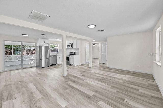 4119 Beacon Square Dr, Holiday, FL 34691 - unfurnished living room featuring baseboards, light wood-style flooring, and a sink