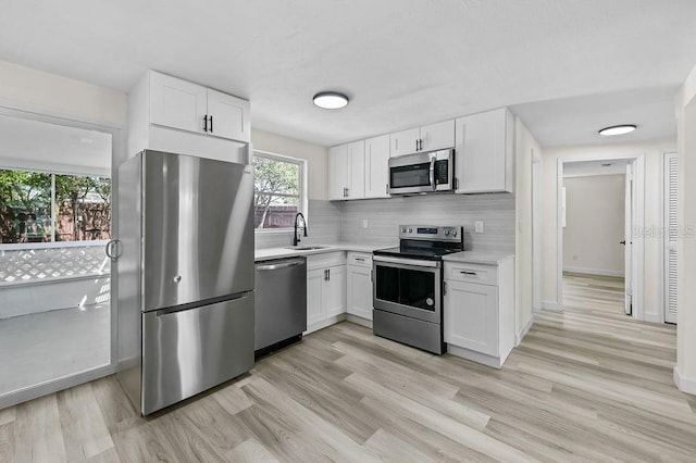 4119 Beacon Square Dr, Holiday, FL 34691 - kitchen with appliances with stainless steel finishes, light countertops, white cabinetry, and light wood-type flooring