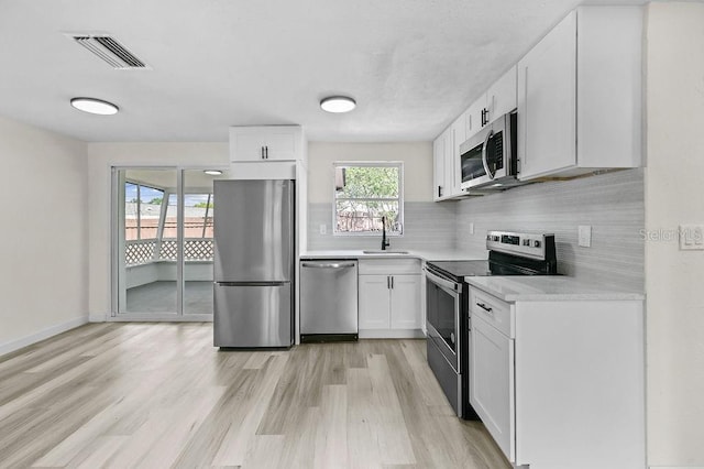 4119 Beacon Square Dr, Holiday, FL 34691 - kitchen featuring appliances with stainless steel finishes, light countertops, a sink, and light wood-style flooring