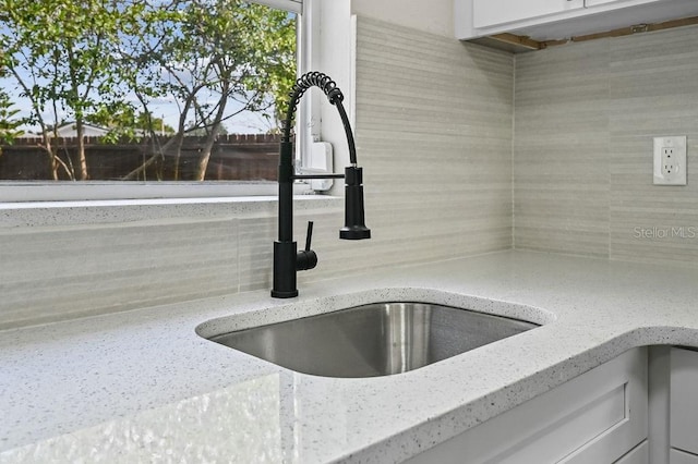 4119 Beacon Square Dr, Holiday, FL 34691 - kitchen view of a sink, decorative backsplash, light stone countertops, and white cabinetry