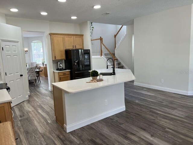 14936 Masthead Landing Cir, Winter Garden, FL 34787 - kitchen with black refrigerator with ice dispenser, dark wood-style floors, light countertops, a sink, and an island with sink