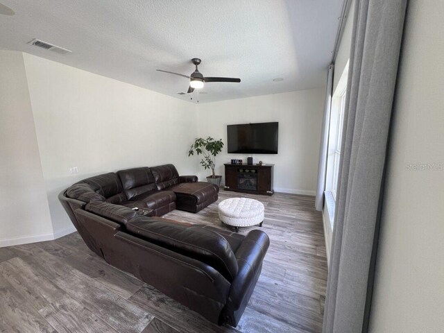 14936 Masthead Landing Cir, Winter Garden, FL 34787 - living area featuring wood finished floors, ceiling fan, baseboards, and a textured ceiling