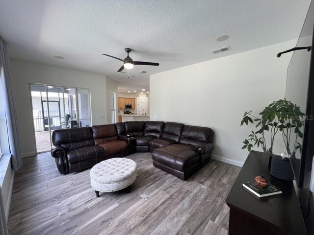 14936 Masthead Landing Cir, Winter Garden, FL 34787 - living area featuring wood finished floors, ceiling fan, a textured ceiling, and baseboards