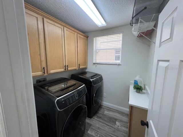 14936 Masthead Landing Cir, Winter Garden, FL 34787 - washroom featuring cabinet space, washing machine and clothes dryer, wood finished floors, baseboards, and a textured ceiling
