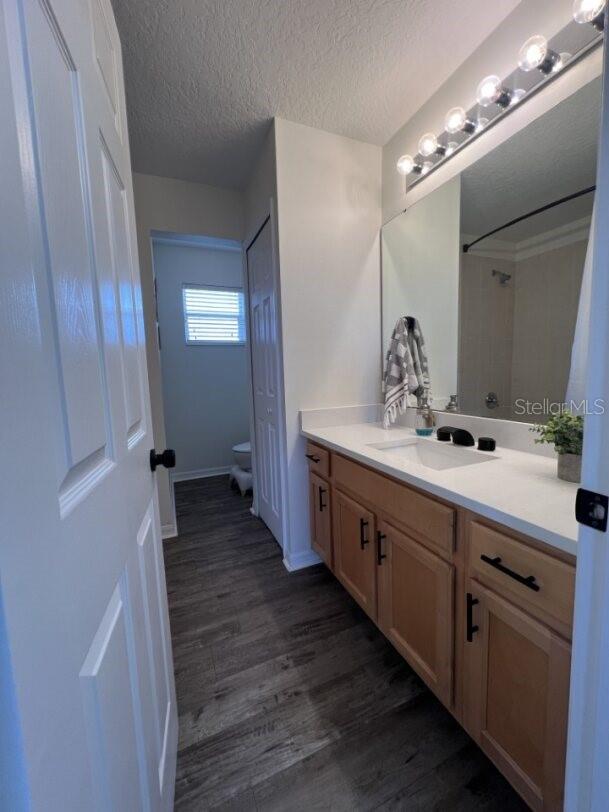 14936 Masthead Landing Cir, Winter Garden, FL 34787 - bathroom featuring vanity, toilet, wood finished floors, a shower, and a textured ceiling