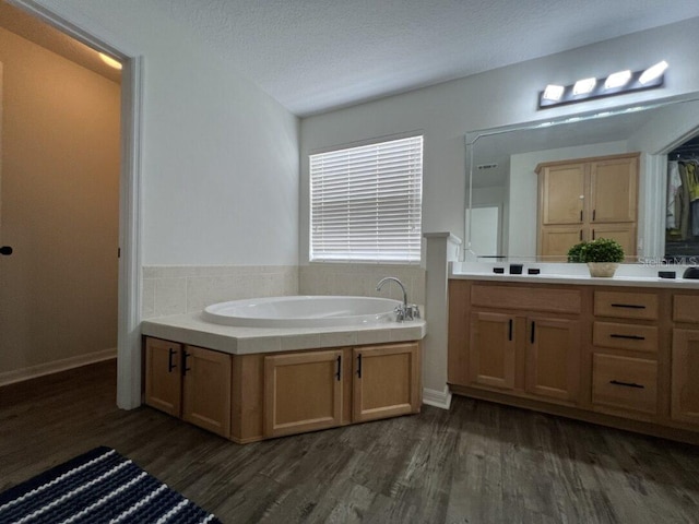 14936 Masthead Landing Cir, Winter Garden, FL 34787 - bathroom with wood finished floors, a bath, double vanity, and a textured ceiling