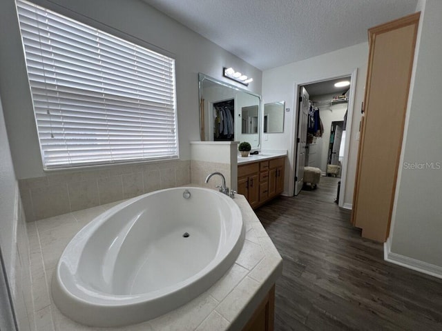 14936 Masthead Landing Cir, Winter Garden, FL 34787 - bathroom featuring vanity, a spacious closet, a bath, a textured ceiling, and wood finished floors