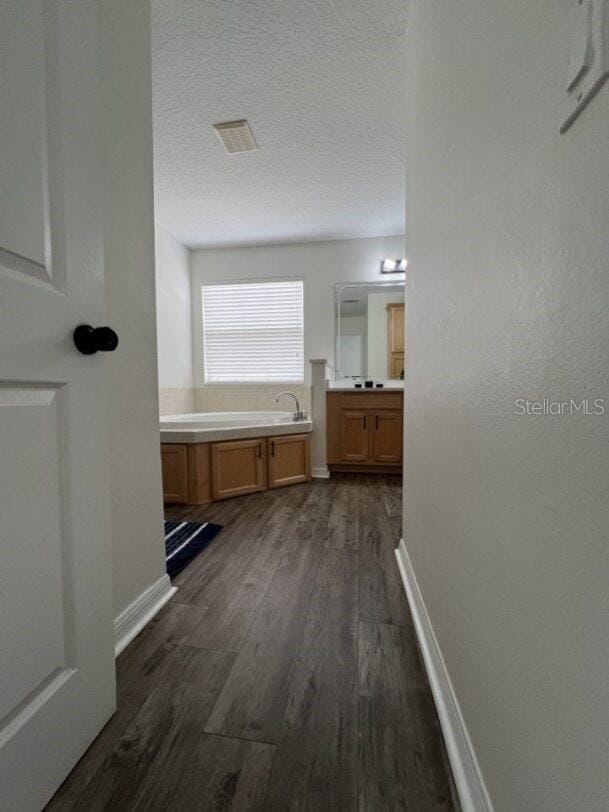 14936 Masthead Landing Cir, Winter Garden, FL 34787 - full bathroom featuring wood finished floors, a bath, vanity, baseboards, and a textured ceiling