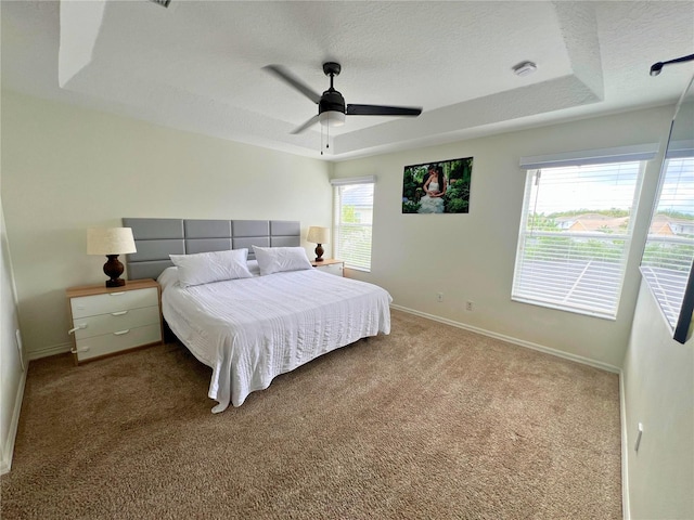 14936 Masthead Landing Cir, Winter Garden, FL 34787 - carpeted bedroom with baseboards, a textured ceiling, ceiling fan, and a tray ceiling