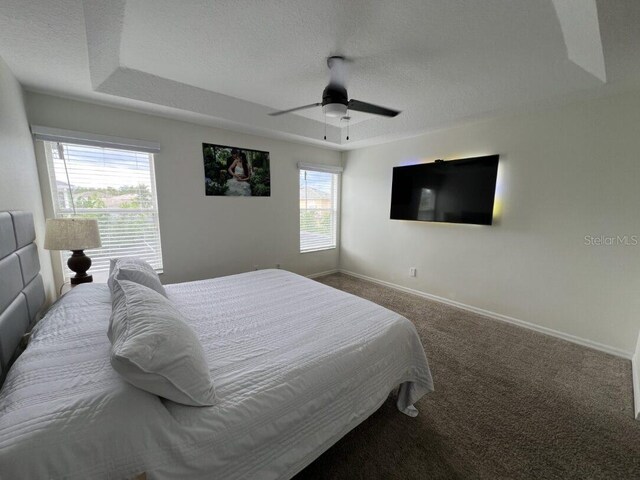 14936 Masthead Landing Cir, Winter Garden, FL 34787 - bedroom with carpet floors, a textured ceiling, baseboards, a tray ceiling, and a ceiling fan
